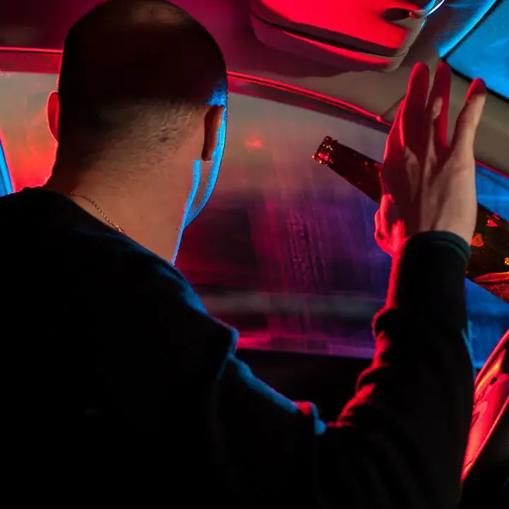 Guy getting stopped with a drink in his hand in the car