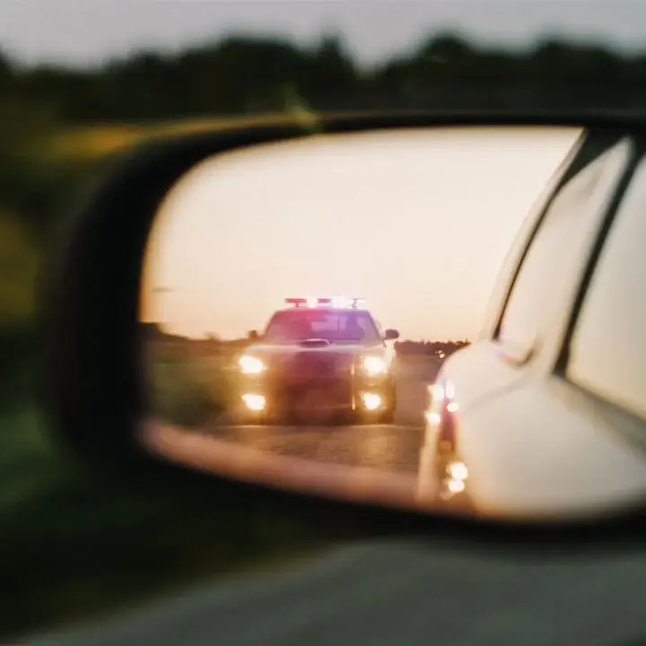 Police with sirens seen through the side mirror