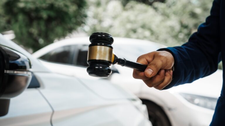 lawyer is holding a wooden gavel and standing in front of a car