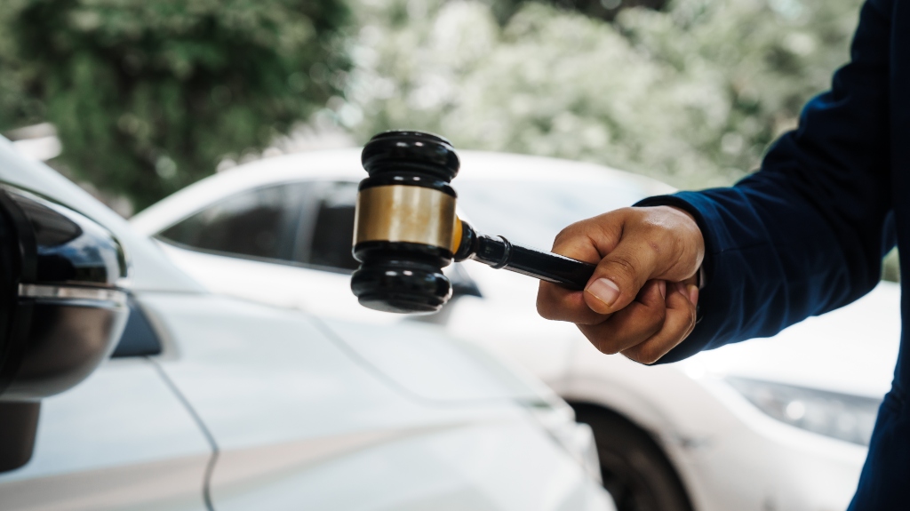 lawyer is holding a wooden gavel and standing in front of a car