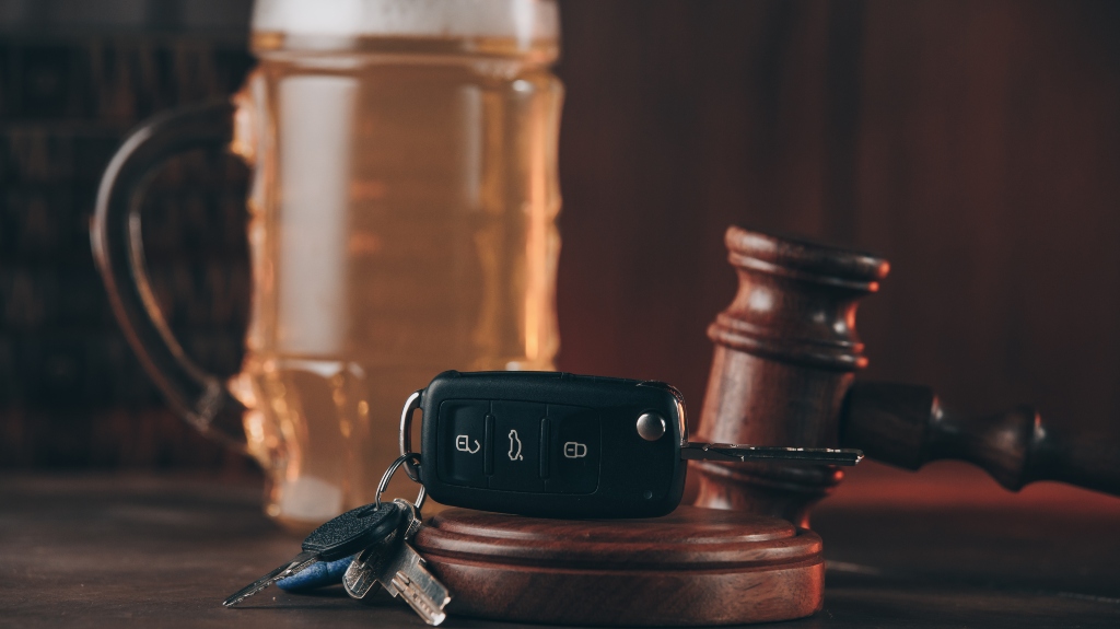 Glass of beer, car keys and judge gavel on a wooden table