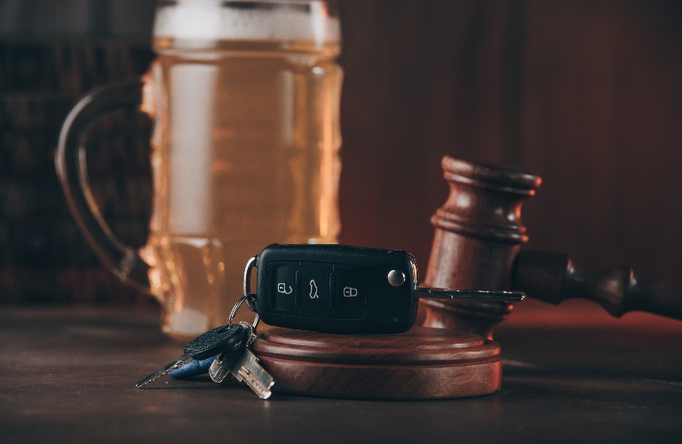 Glass of beer, car keys and judge gavel on a wooden table