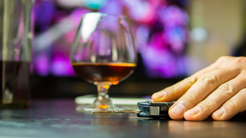 man drinking whisky at bar and taking car key from table