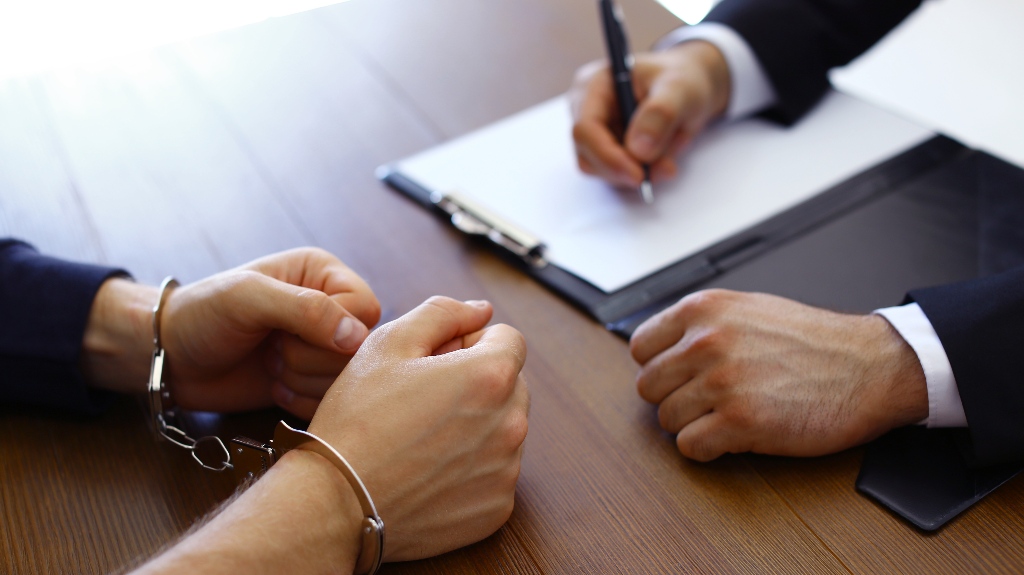 Man in handcuffs is consulting with lawyer