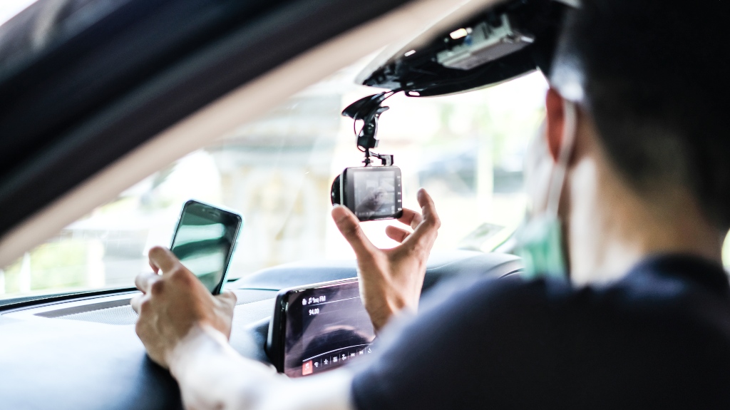 Hand with Car Camera and Smartphone Inside Car and Blur Man as a Foreground